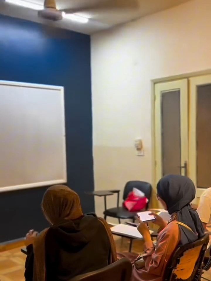 Students in an iLearn classroom facing the navy wall and whiteboard